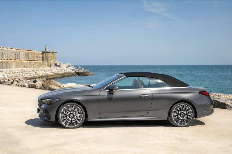 2024 Mercedes-Benz CLE Cabriolet in gray with tan upholstery black top up parked on sand near the ocean with an old fort in the background.