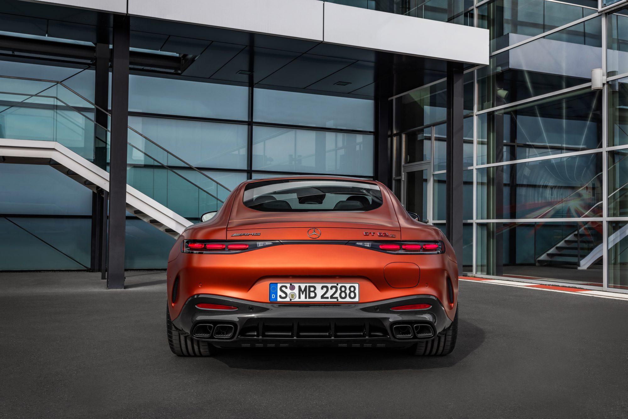 2025 Mercedes-AMG GT 63 S E Performance direct rear view parked in front of a glass-walled building.
