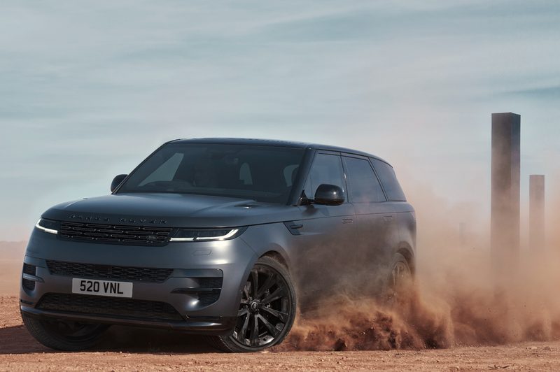 025 Range Rover Sport Dynamic SE with Stealth Pack sliding into a left turn on desert sand with black monoliths in the background.