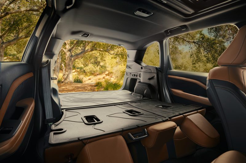 2025 Subaru Forester on a forest road showing the cargo area with the second row seats folded forward and back hatch open.