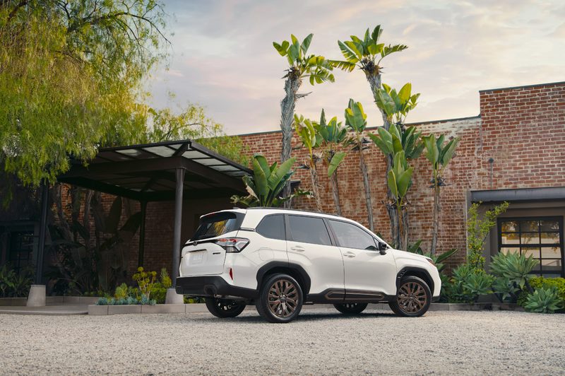 2025 Subaru Forester parked on a stone drive in front of a contemporary brick and glass-sided house.