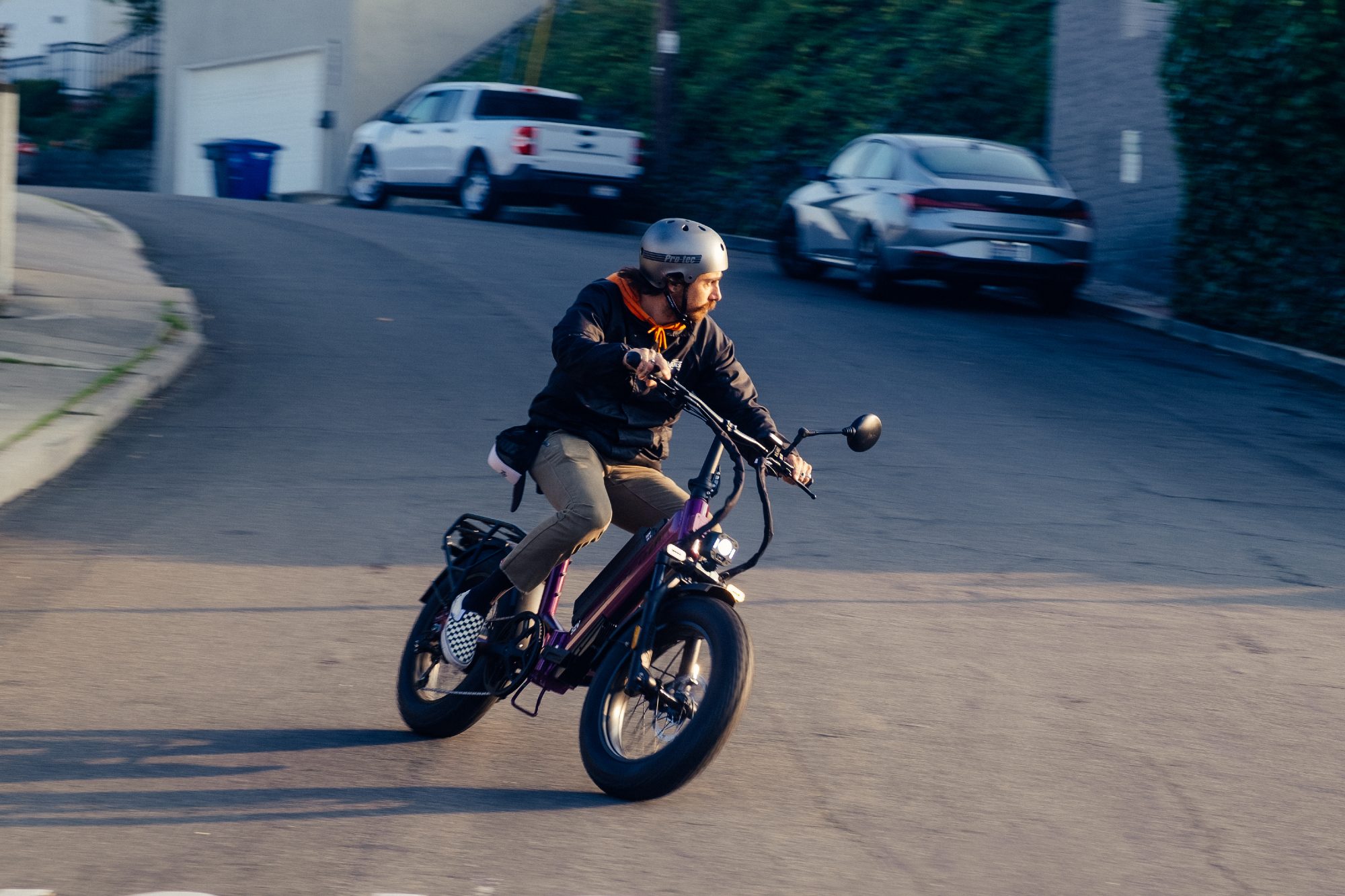 A rider turns on a steep downhill street on a Purple Haze Jiuiced Bikes JetCurrent Pro e-bike.