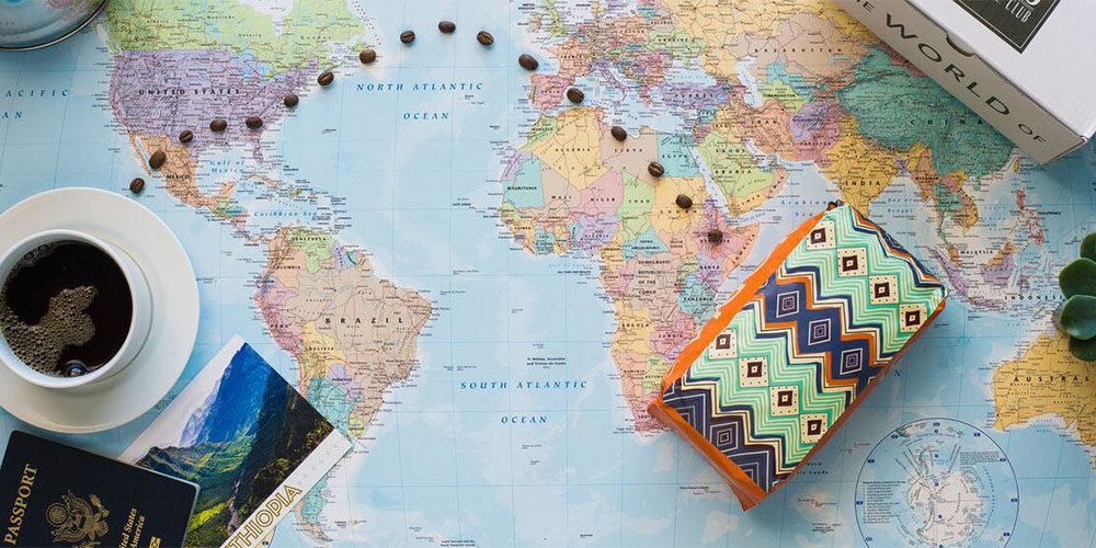 A world map with a cup of coffee and a passport near it.