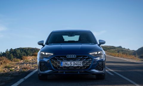 Blue 2025 Audi S3 direct front view with the car driving on a mountain road with rocks and trees on either side.