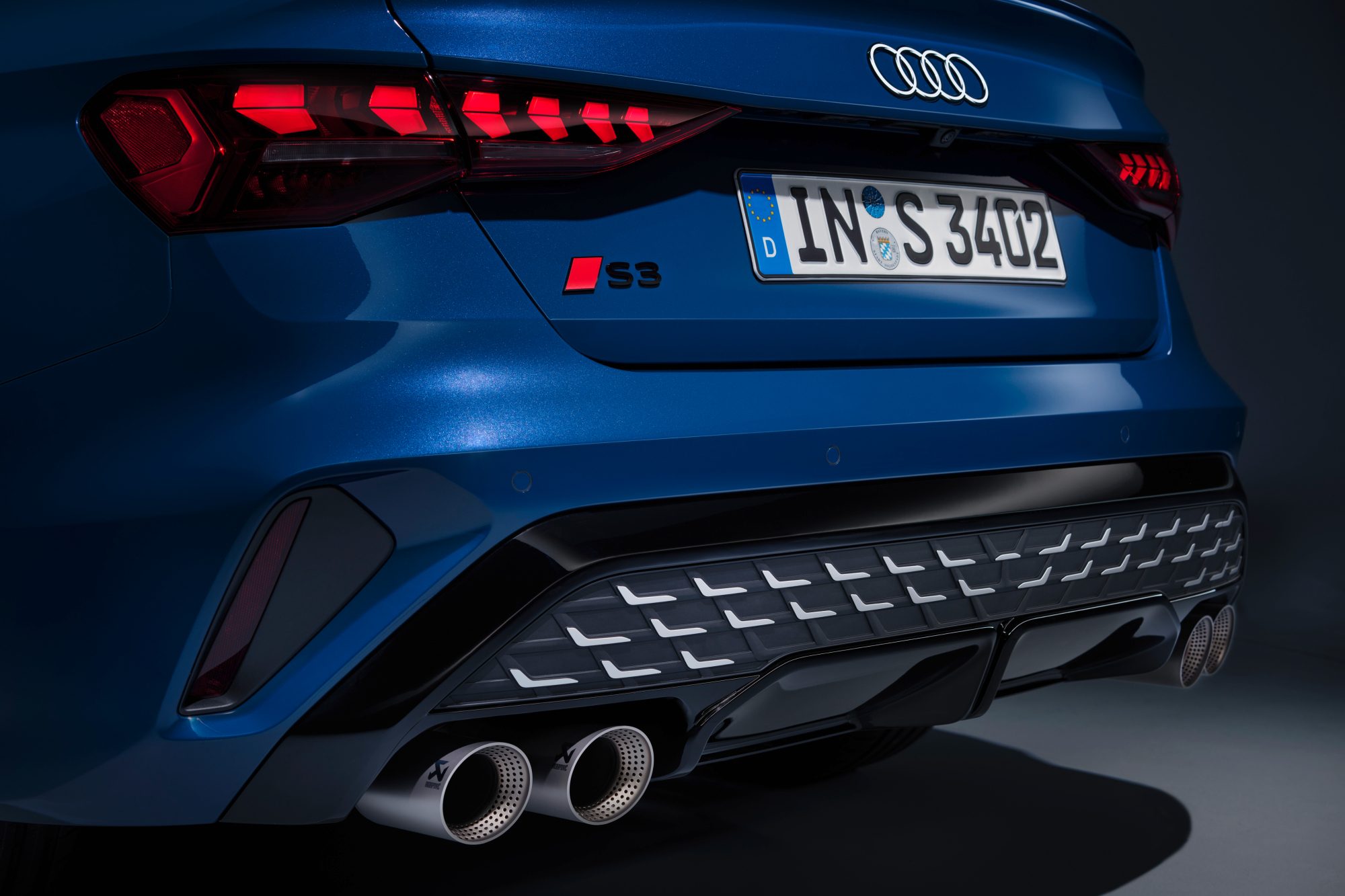 Blue 2025 Audi S3 left rear view across the back of the car with four exhaust pipe tips in view.