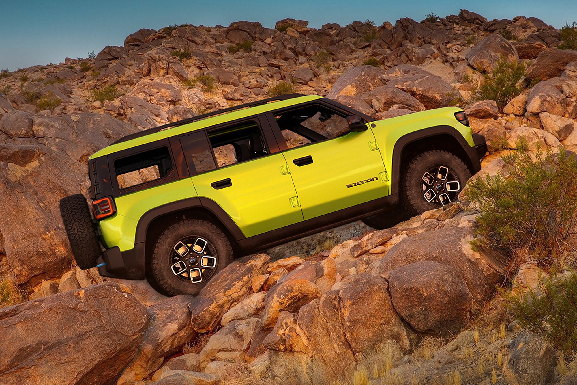 Bright yellow Jeep Recon concept EV in driving up a rocky incline.