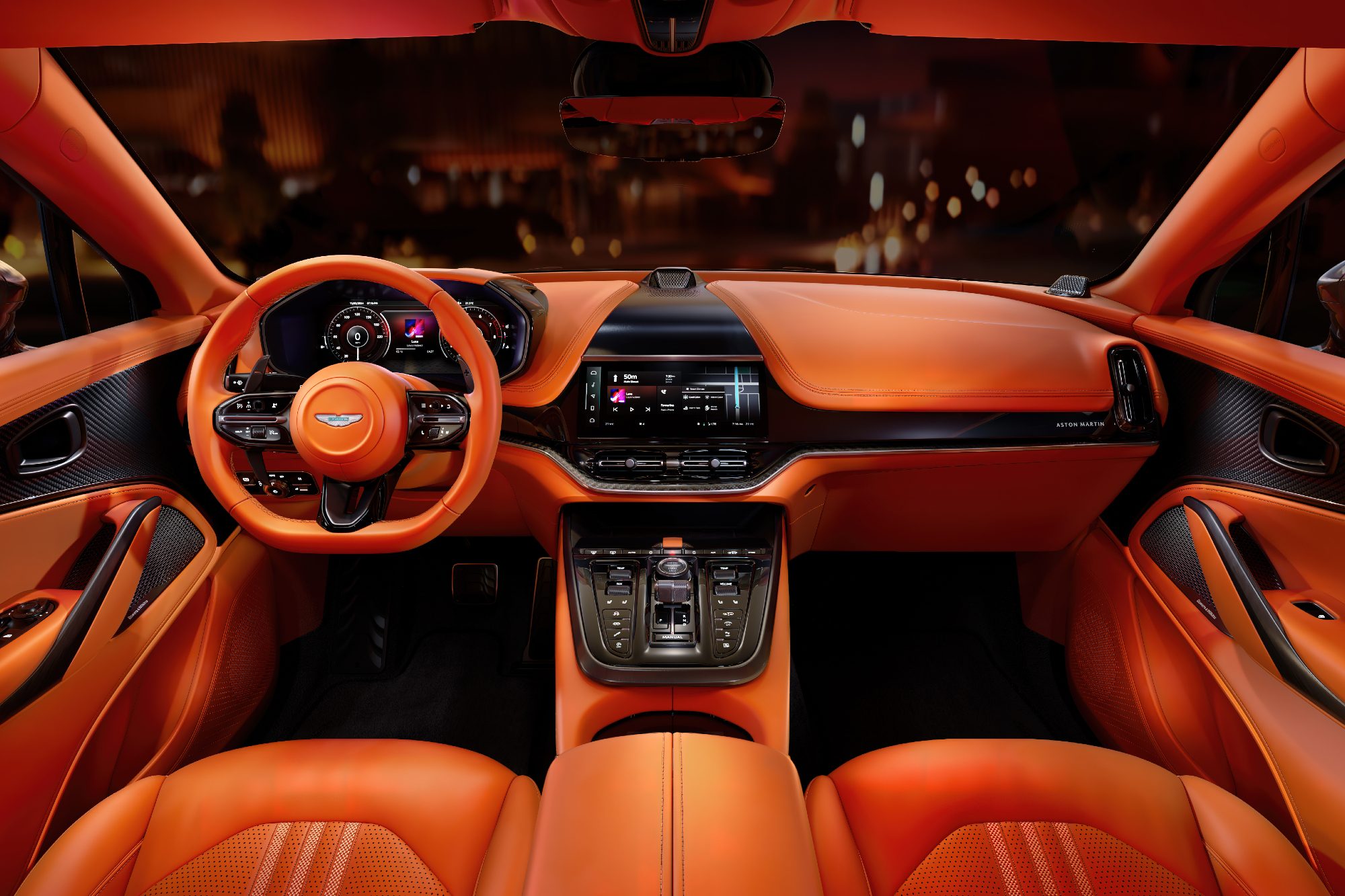 Front seat interior shot of seats and dashboard of Aston Martin DBX707 with blurred city street lights visible through the windshield.