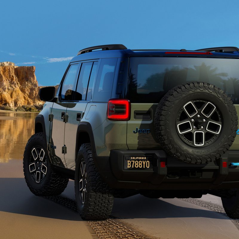 Green Jeep Recon concept EV on a beach with hillls in the background left rear three-quarter shot.