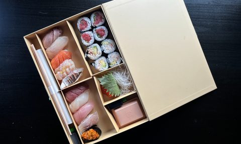 Joji box sushi on black table.