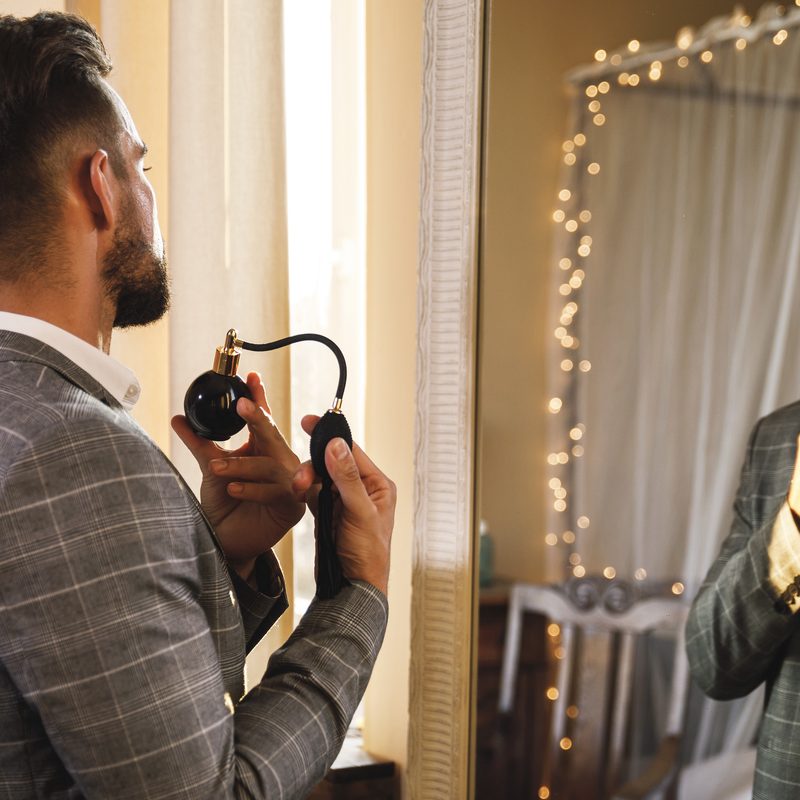 Handsome bearded man is using atomizer nozzle with perfume