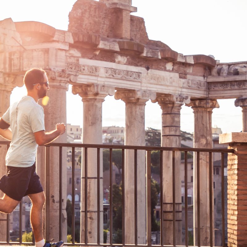 Jogging in front of the Roman Forum at sunrise. Historical imperial Foro Romano in Rome, Italy from panoramic point of view