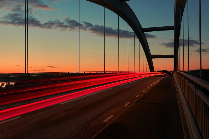 Sunset over bridge with passing taillights