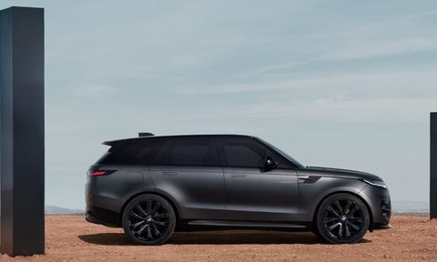 Right side profile shot of a 2025 Range Rover Sport Dynamic SE with Stealth Pack parked on desert sand between two black monoliths.