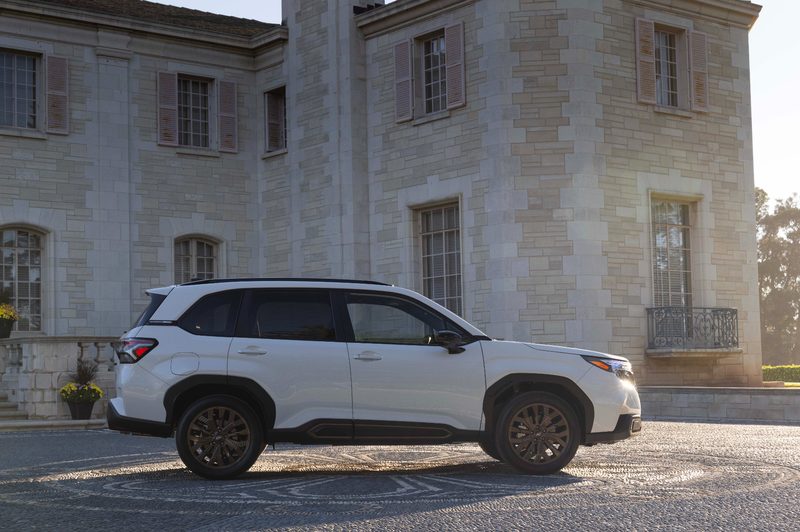 Right side profile shot of a 2025 Subaru Forester parked on a stone drive in front of a multiple story stone mansion