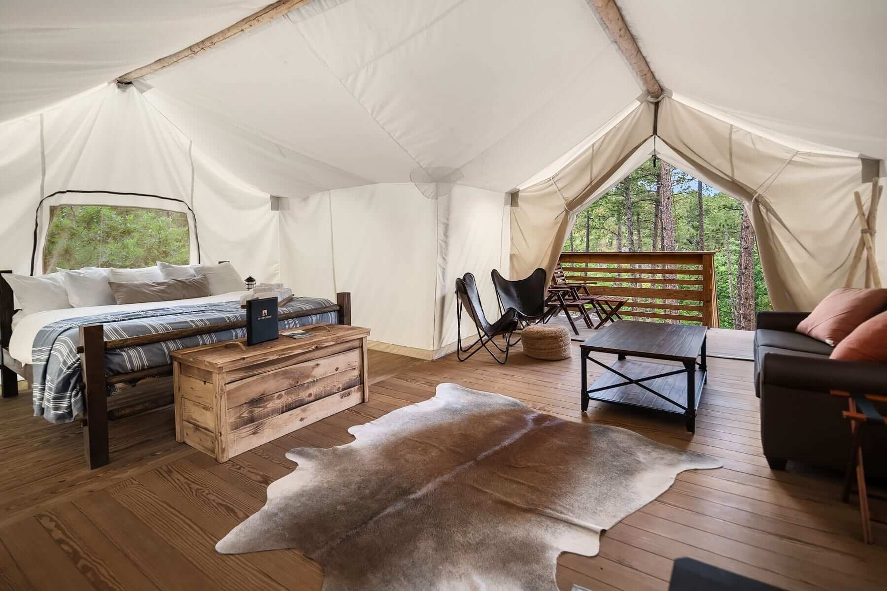 A large white glamping tent with a bed and a porch