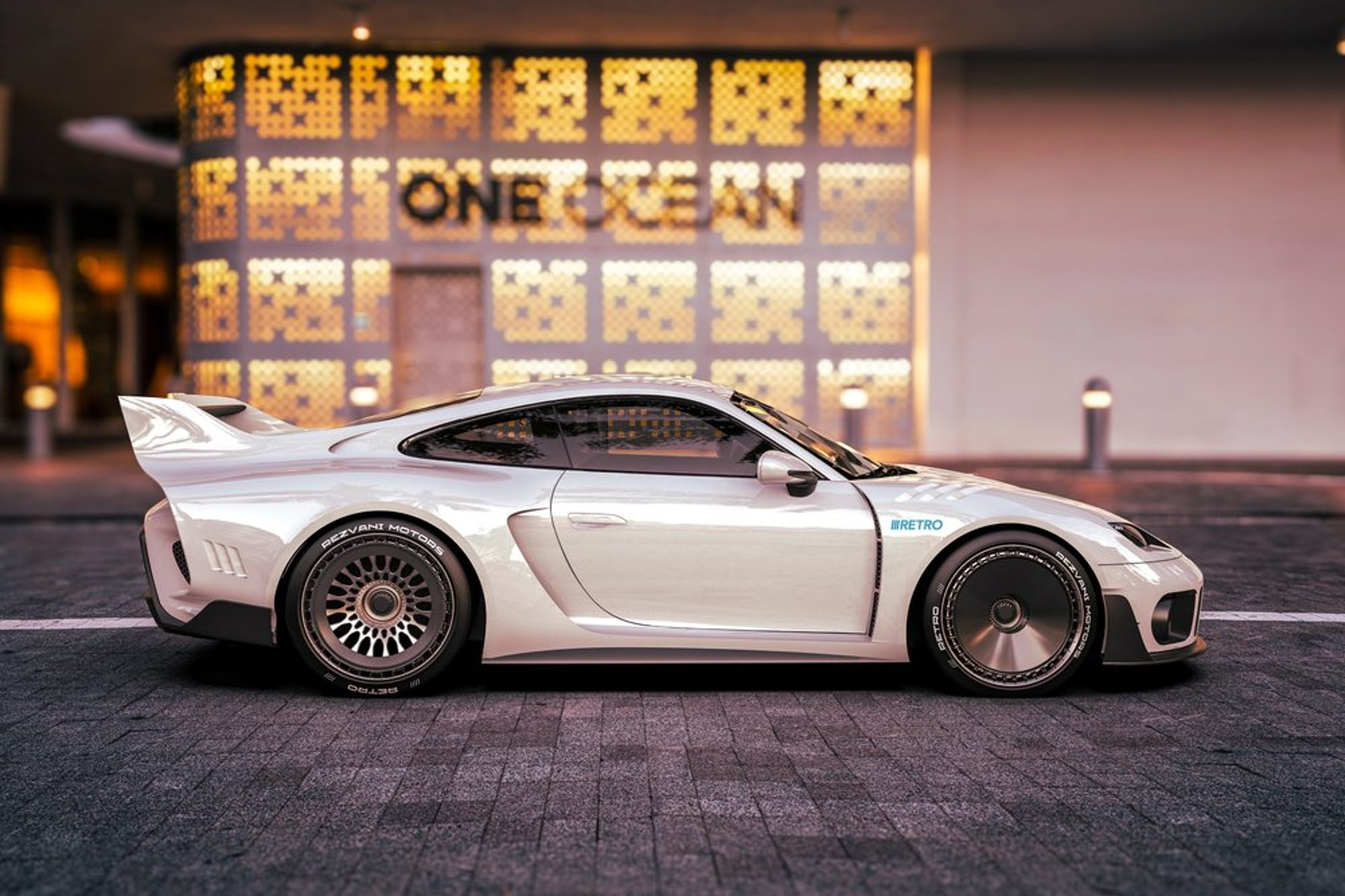 White Rezvani Retro Porsche 911 to Porsche 935 conversion parked in front of a commercial building right profile.