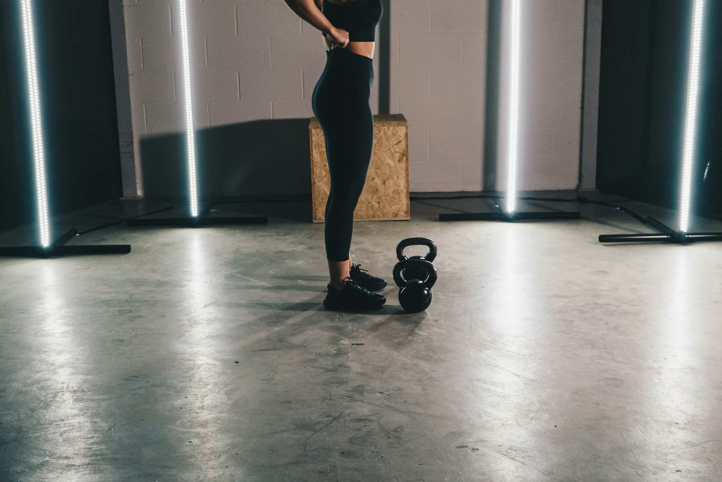 woman wearing leggings standing in gym next to kettlebell