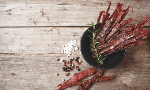 beef jerky sticks in black container on wooden table
