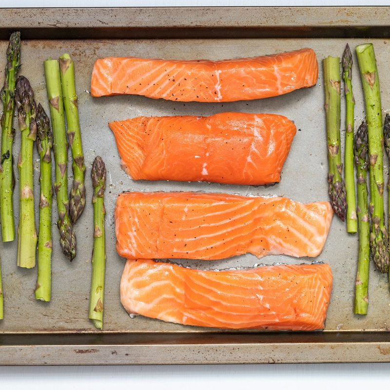 Raw salmon on sheet tray with asparagus