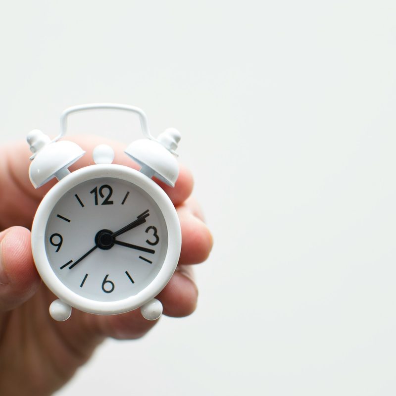 Hand holding a little white clock