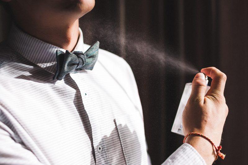 Man applies spray cologne and smells the fragrance