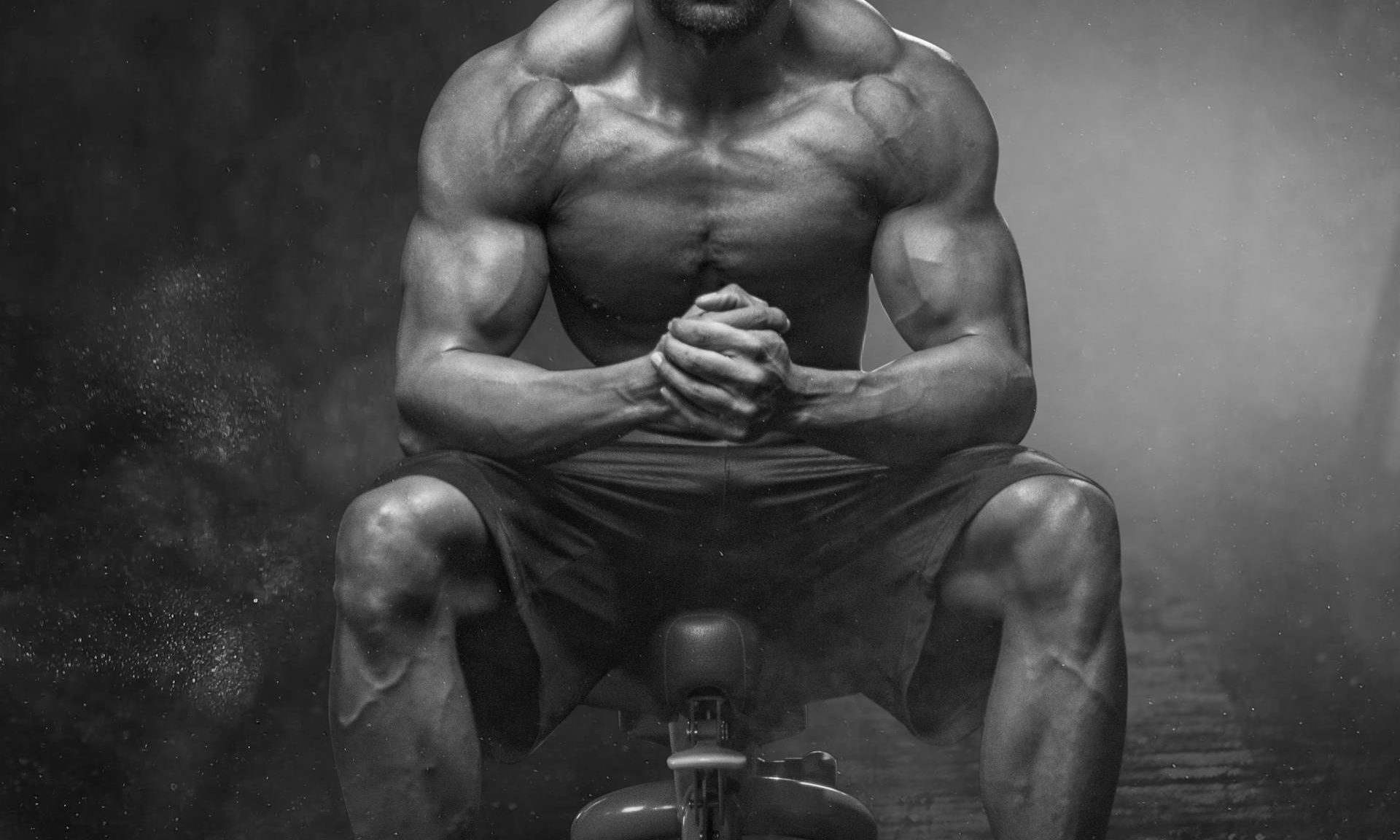 strong man black and white image sitting on gym bench