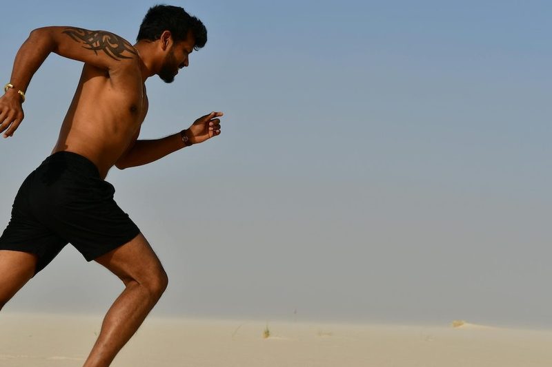 a close up of a shirtless man running outside