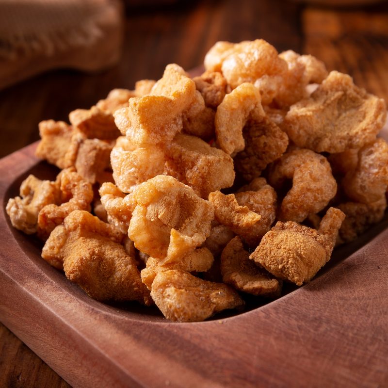 Chicharrones. Deep fried pork rinds, crispy pork skin pieces, traditional mexican ingredient or snack served with lemon juice and red hot chili sauce.