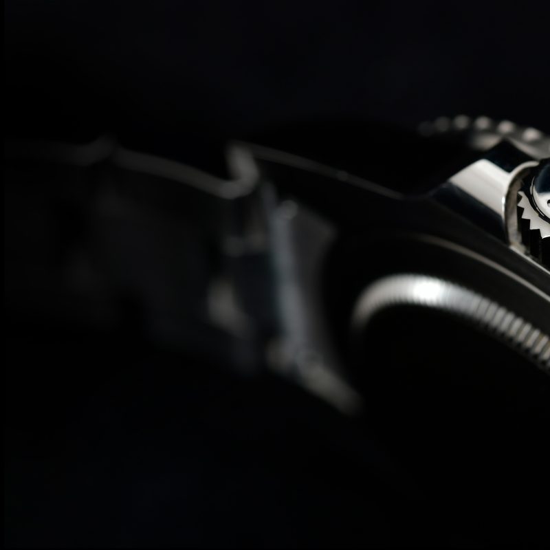 Close-up view of the side of a Rolex watch GMT-Master II "Batman"40mm Steel Ceramic Men's Wrist watch on black background