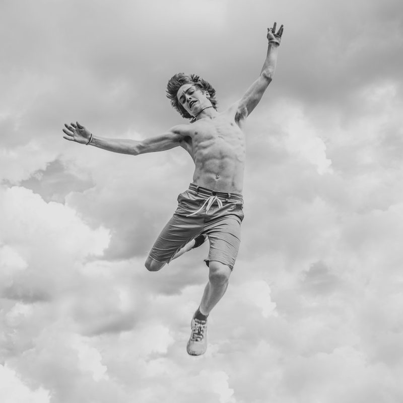 Shirtless man jumping high in the air in black and white