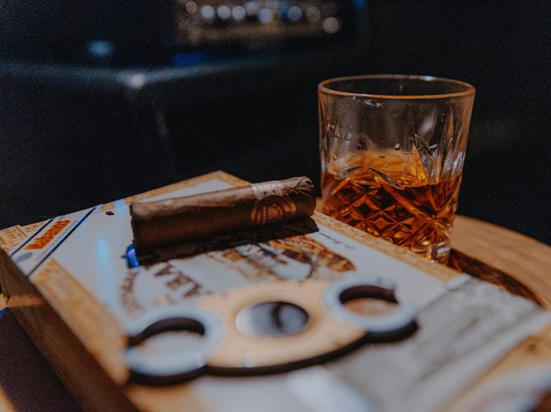 Small cigar on prep tray with a drink and cutter