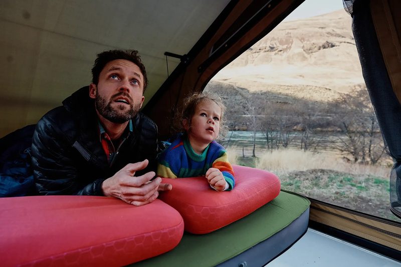 Young man with a child inside the Super Pacific CloudCap pop-up rooftop camper van tent.