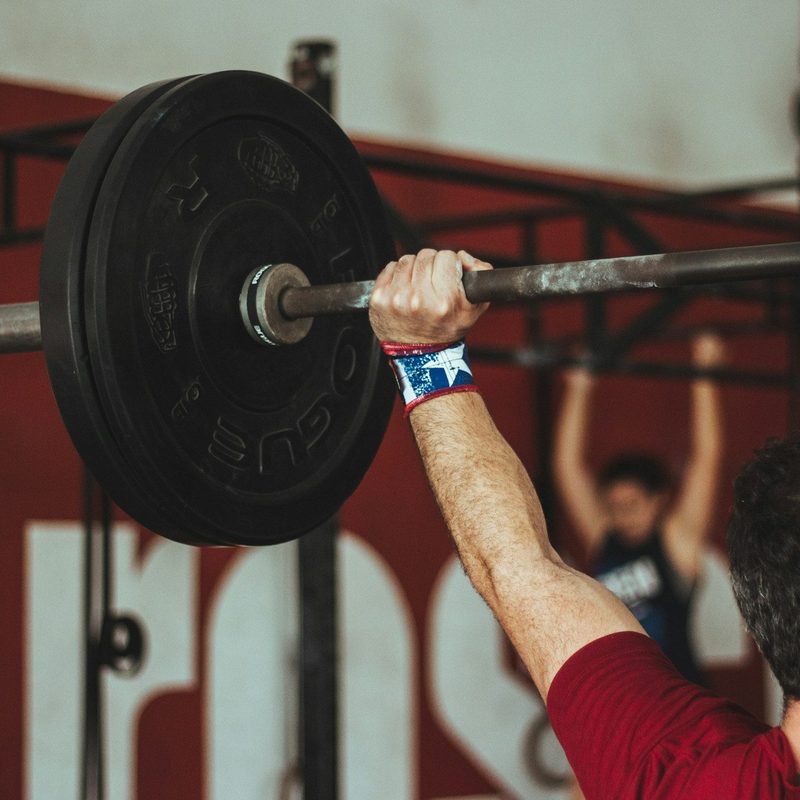 push press exercise man lifting weight over head in gym