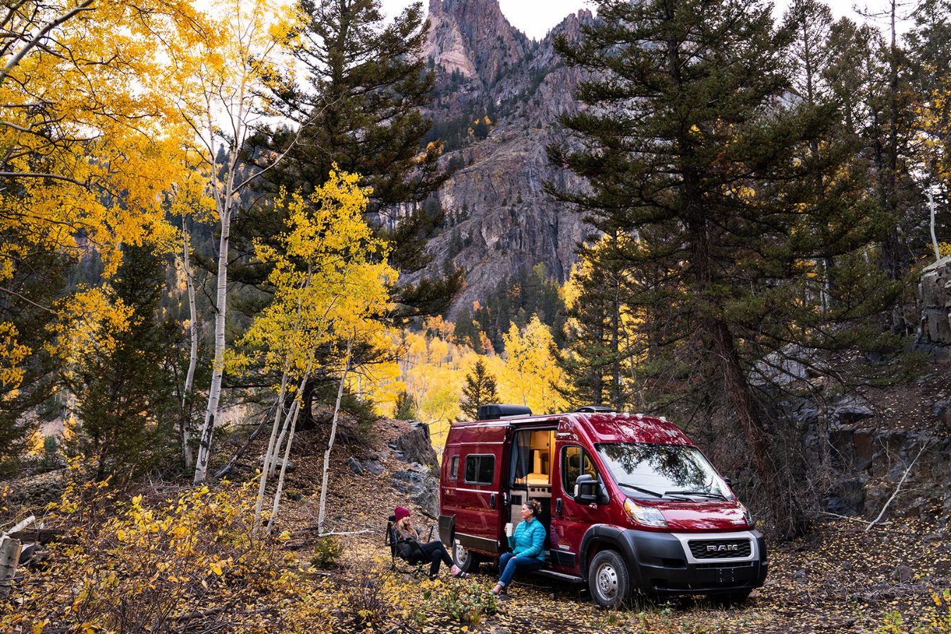 Couple relaxing outside a Winnebago Solis camper van.