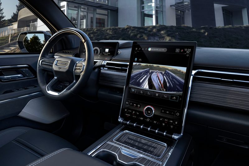 2024 GMC Sierra EV Denali Edition 1 interior view of the driver seat and dashboard including a view of the truck bed contents on the large center display,