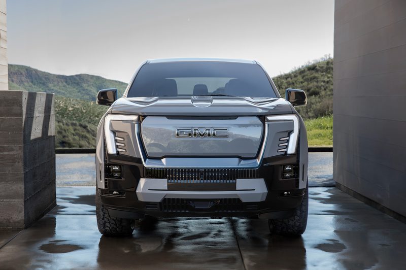 2024 GMC Sierra EV Denali Edition 1 parked on a wet cement floor under next to a concrete buiding in a high desert area.