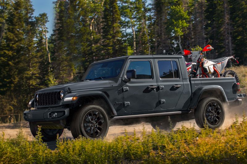2024 Jeep Gladiator Nighthawk limited edition of 200 driving on a dirt road in a forest,