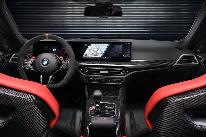 2025 BMW M4 CS interior shot of front seats, dashboard, and center conole parked in a garage witha corrugated wall.
