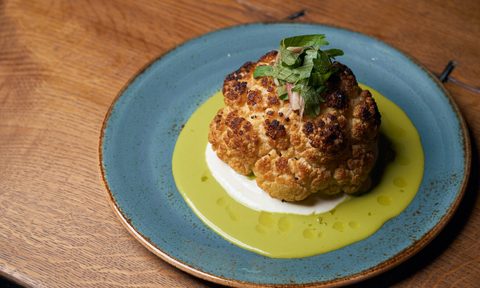 whole roasted cauliflower on blue plate