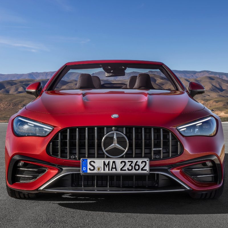 Mercedes-AMG CLE 53 Cabriolet front view red with top down parked on asphalt with hills in background.