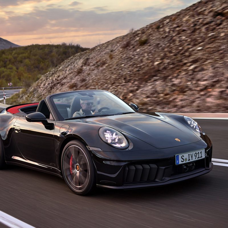 Porsche 911 Cabriolet hybrid front right three-quarter view driving on a mountain road.