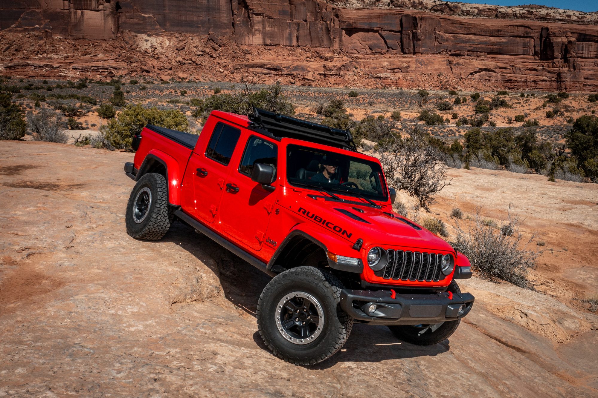 Red 2024 Jeep Gladiator Rubicon descending rocky rise in Utah