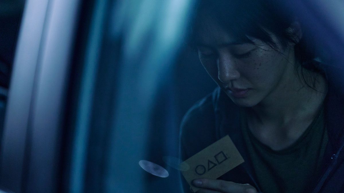 A woman holds a player card in Squid Game season 2.