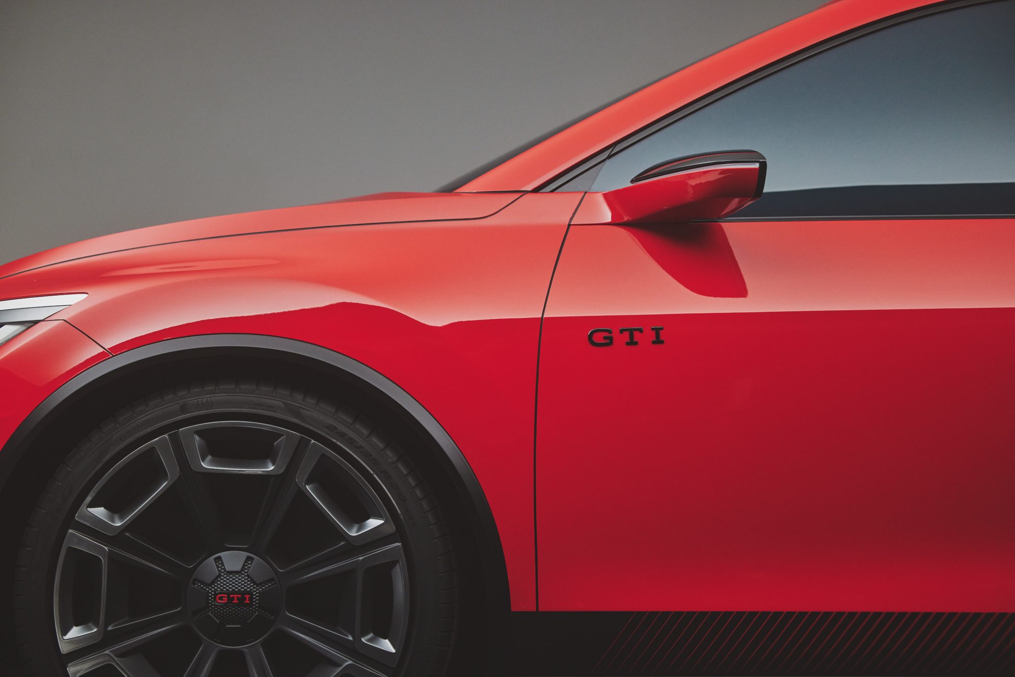 Volkswagen GTI EV concept in red left front quarter panel showing the wheel and driver's door with black GTI badging.