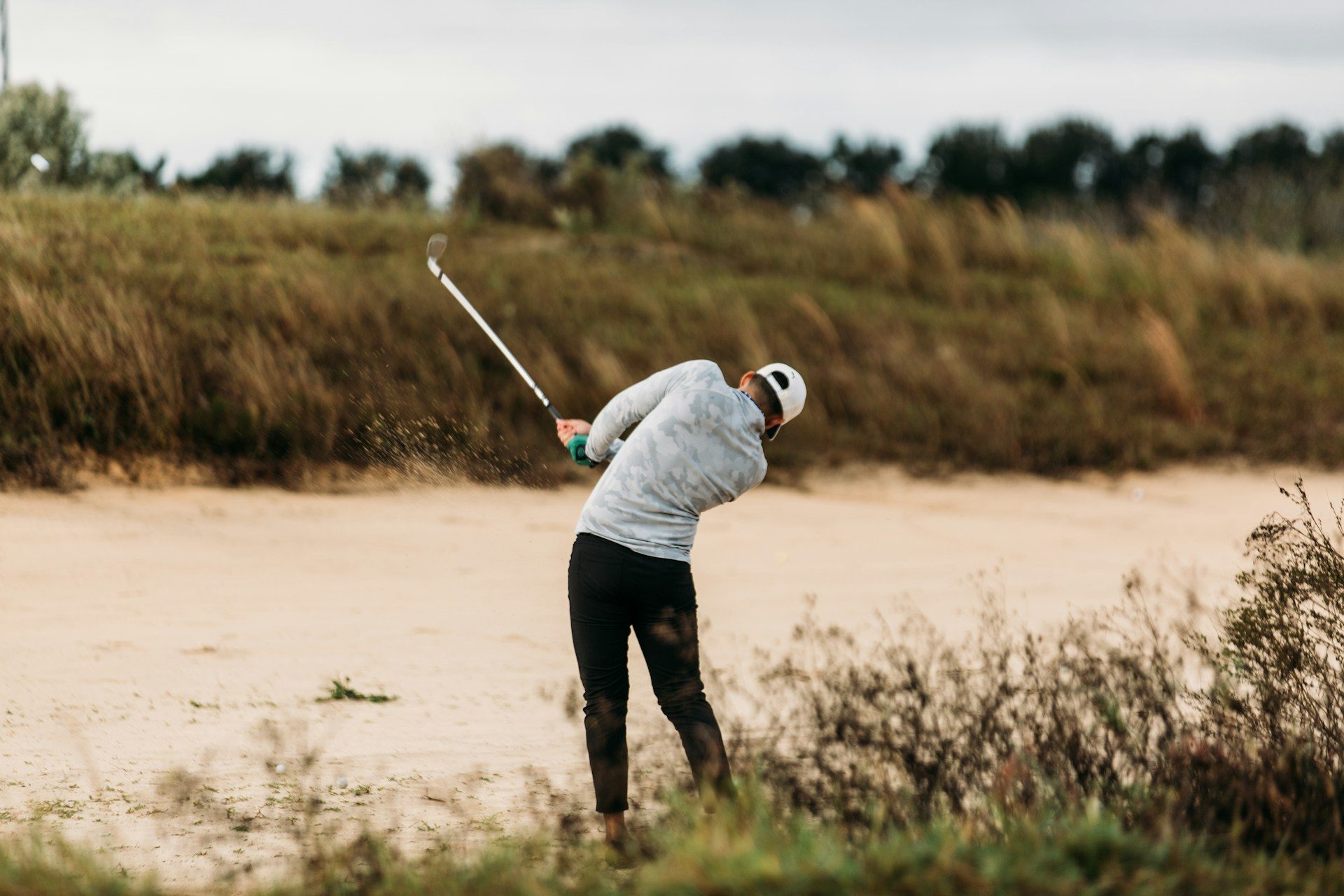 Man golfing near sand.