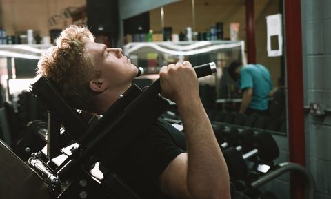 blonde-haired man doing a hack squat on a hack squat machine
