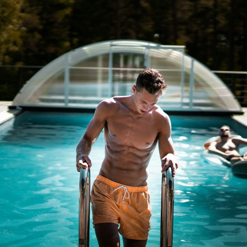 Man getting out of pool with orange swim bottoms on