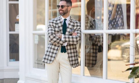 man in suit and tie leaning on building
