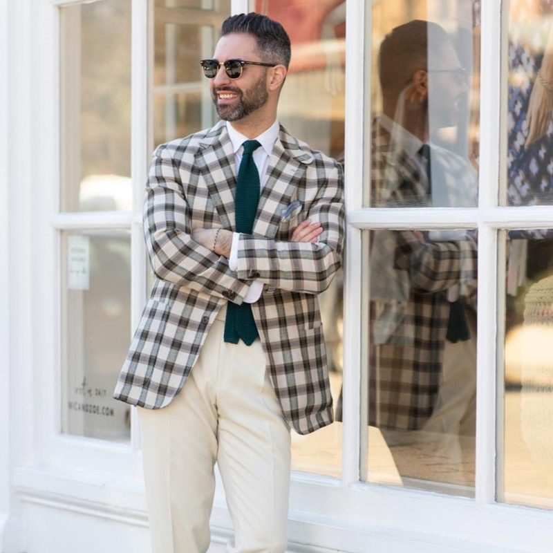 man in suit and tie leaning on building