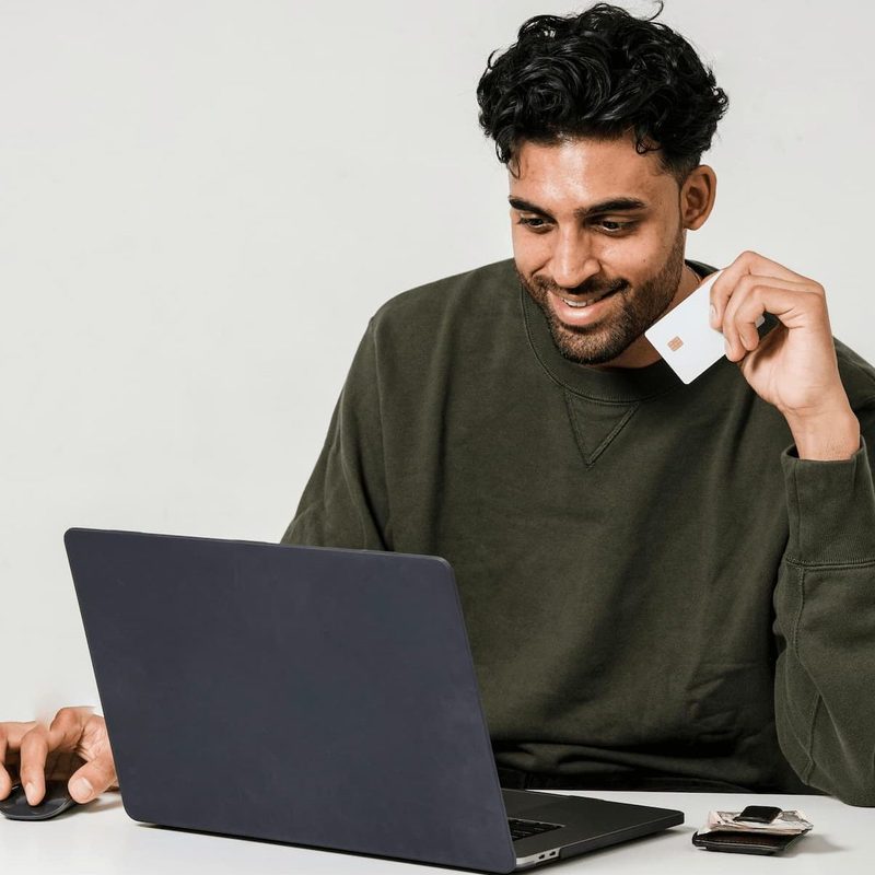 man holding credit card looking at computer
